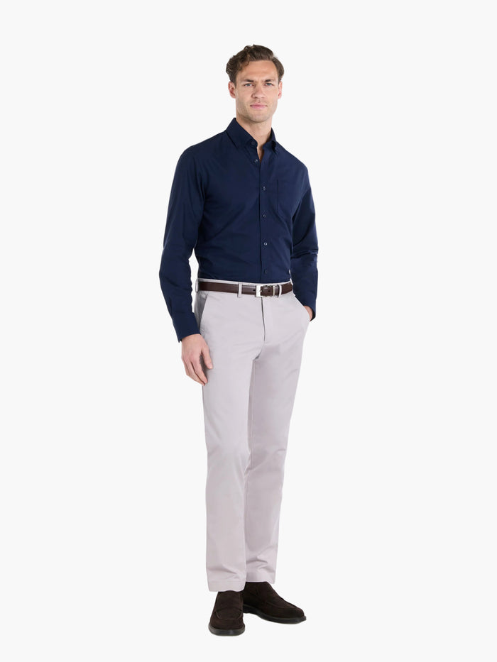 Man wearing a navy shirt and light gray trousers on a white background