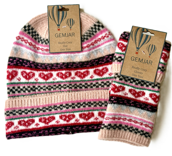 A knit beanie and matching glove set from Gemjar, featuring a Fair Isle pattern with red hearts, black and pink stripes, and light blue accents on a cream base. Both items are shown with their original kraft paper tags.