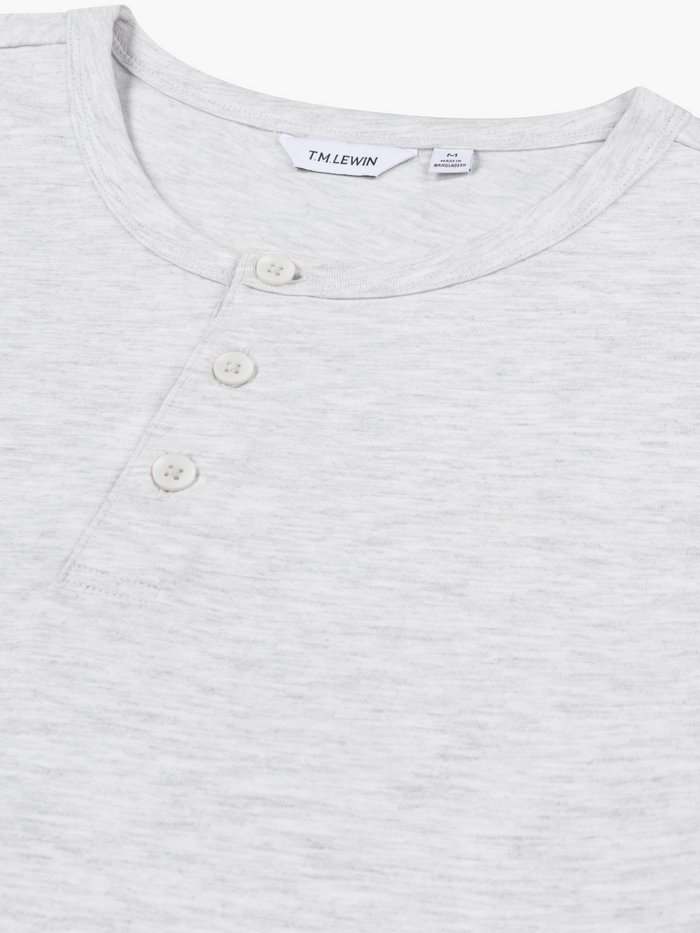 Close-up shot of the placket buttons on a light grey Henley shirt's neckline