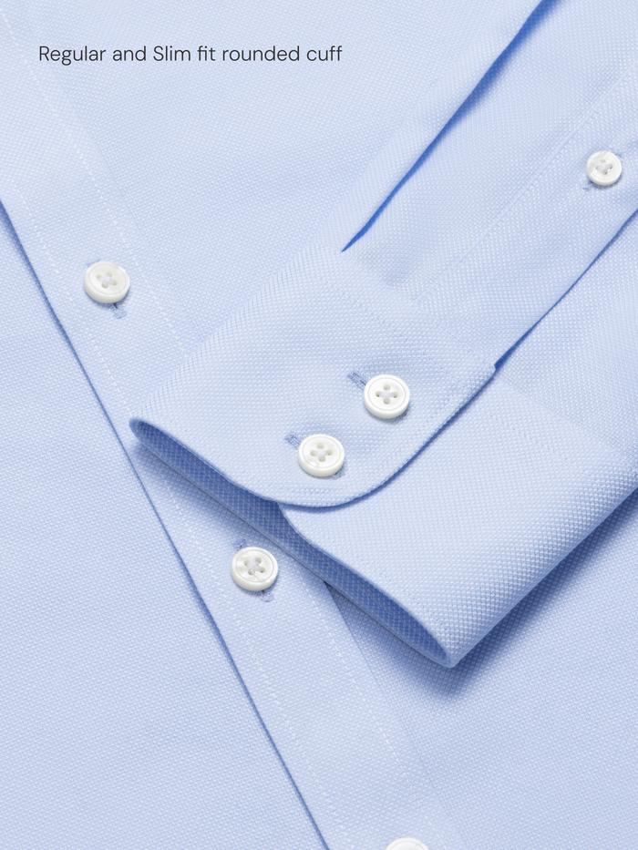 Close-up of a light blue shirt with white buttons and a rounded single cuff